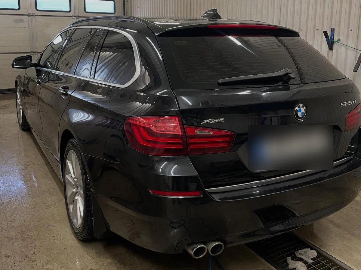 Svart BMW 5-serie Touring efter rekond, fotograferad bakifrån i tvätthallen